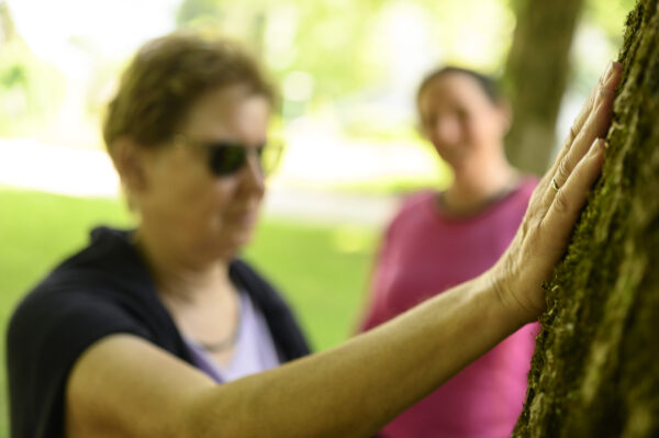 Eine Dame die einen Baum mit der Hand berührt